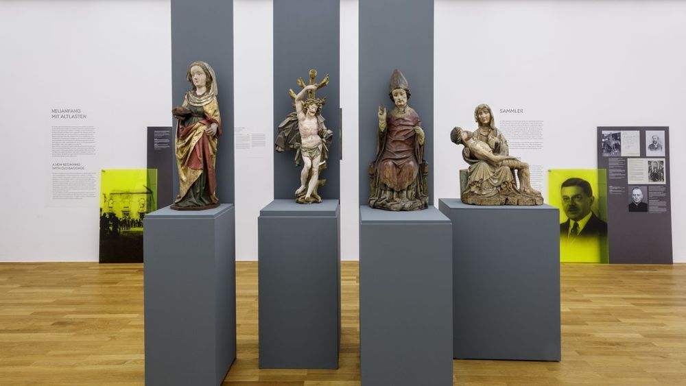 Ausstellungsansicht der Kunstausstellung im Zeppelin Museum, vier Skulpturen verschiedener Personen aus Holz.