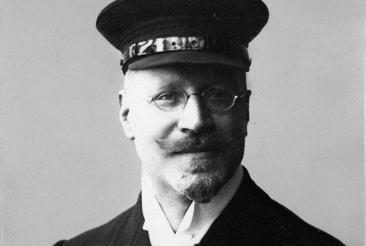 Die historische Aufnahme zeigt ein Porträt von Theodor Kober, der eine Brille und eine Kapitänsmütze trägt.