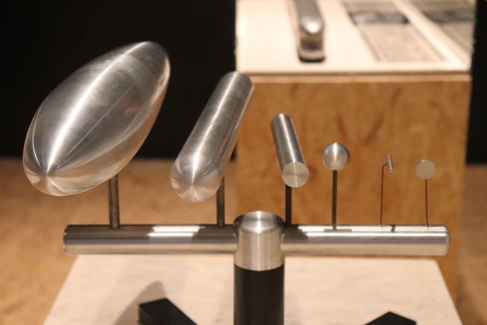 Die Ausstellungsansicht zeigt ein Vergleichsmodell, das aus metallischen Objekten besteht, die nebeneinander aufgereiht sind.