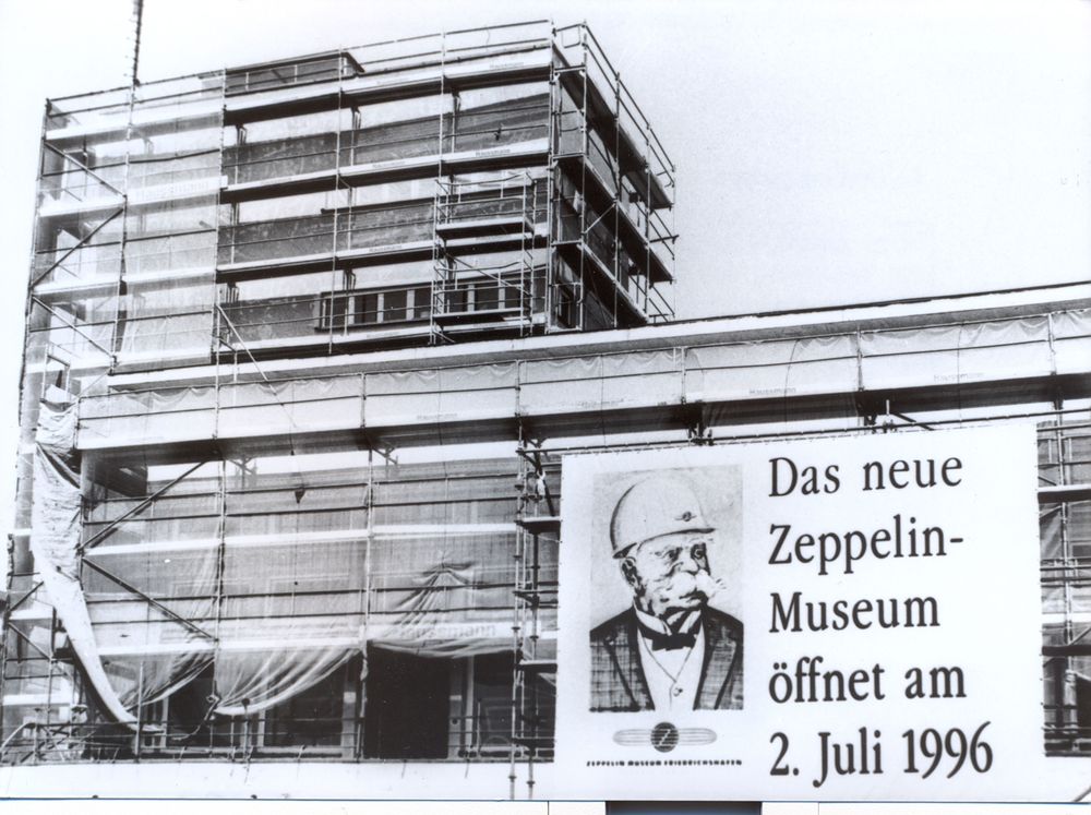 Der eingerüstete Hafenbahnhof und ein angebrachtes Banner mit der Aufschrift: Das neue Zeppelin Museum öffnet am 2. Juli 1996.