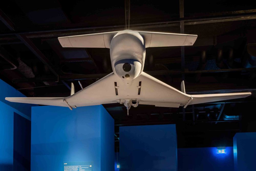 Von der Decke hängt das Modell einer weißen Drohne, die stark einem Flugzeug ähnelt.