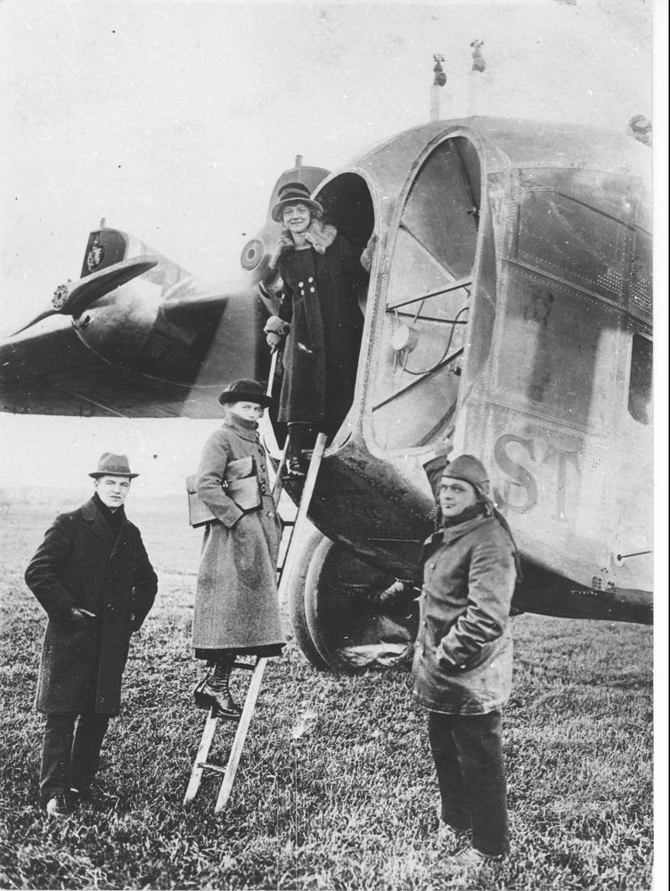Die historische Aufnahme zeigt den Einstieg von Passagieren in den Rumpfbug eines Flugzeugs.