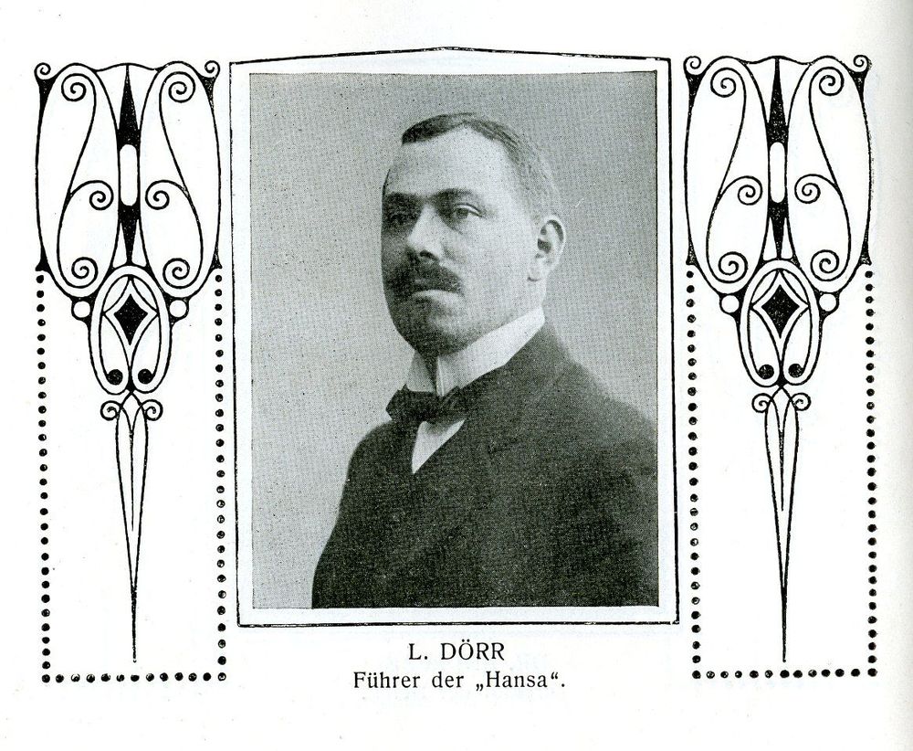 Brustbild des Luftschiffkapitäns Dörr, Führer der „Hansa“. Er trägt einen Schnauzbart und hat seitlich gescheitelte Haare. Das Portrait befindet sich zwischen zwei Jugendstilornamenten.