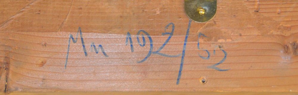 Die Aufnahme zeigt ein Stück Holz, auf dem mit blauer Schrift ein Buchstabenkürzel und eine Nummer steht.