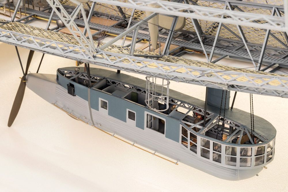 Die Aufnahme zeigt ein Detail eines Luftschiffmodells. Man kann in die Gondel blicken, in der mehrere kleine Figuren an der Arbeit sind.