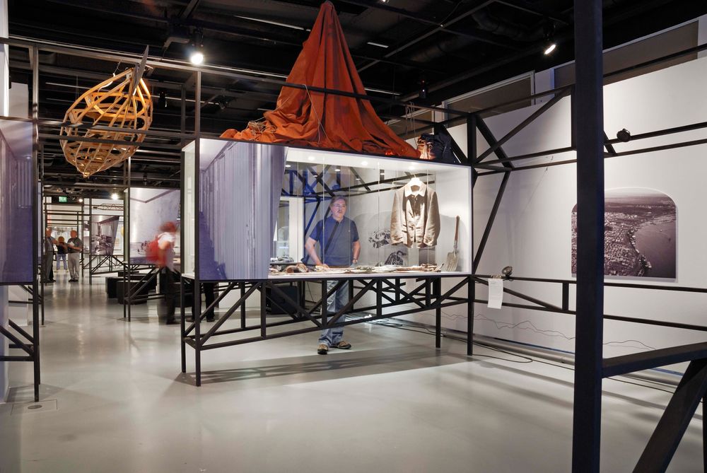 Die Ausstellungsansicht zu "66 Grad 30 Minuten Nord. Luftschiffe über der Arktis" zeigt einen Mann, der Exponate in einer Vitrine vor sich betrachtet.