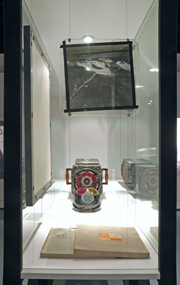 Die Ausstellungsansicht zu "66 Grad 30 Minuten Nord. Luftschiffe über der Arktis" zeigt eine Vitrine, in der sich verschiedene Exponate befinden und ein Bild von der Decke hängt. 