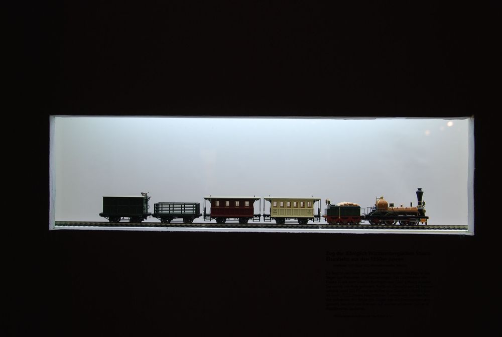 In einer beleuchteten Aussparungen an der Wand ist eine kleine Modell-Eisenbahn aufgestellt, die von einem dahinter liegenden Licht beleuchtet werden.