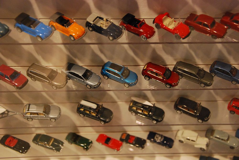 Mehrere kleine Modell-Autos stehen nebeneinander und untereinander in einem Regal aufgereiht.