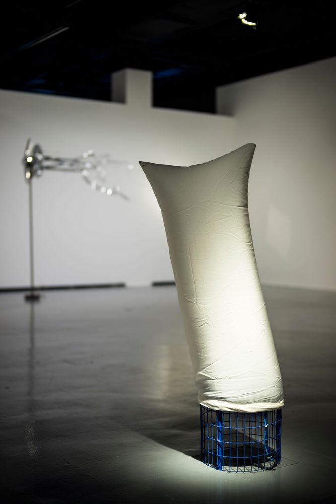 Eine Installation aus weißem, schlauchförmigem Stoff ist über eine Art Gebläse am Boden gespannt und bläst sich auf.
