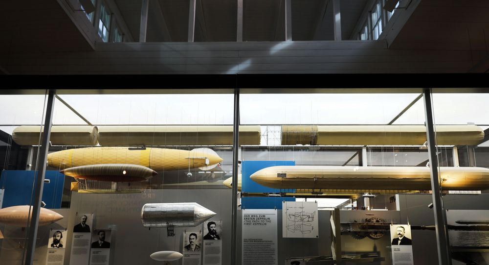 In einer großen Glasvitrine hängen mehrere Luftschiffmodelle, sowie Bilder und Ausstellungstexte.