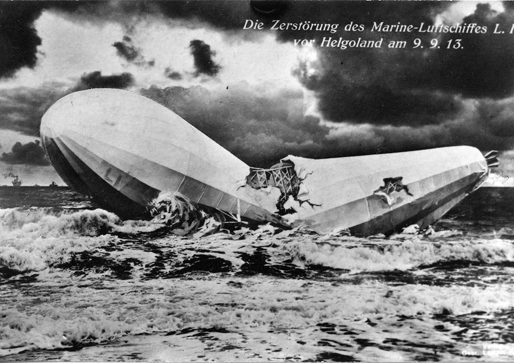 Die schwarz-weiß Abbildung zeigt ein n der Mitte brechendes Luftschiff, welches in einem stürmischen Meer versinkt. 