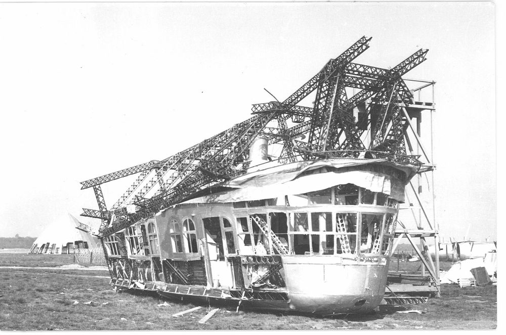Die Gondel steht auf freiem Feld. Oben sind die Träger des Luftschiffs noch teilweise angebracht. Der Rest des Zeppelins wurde entfernt.