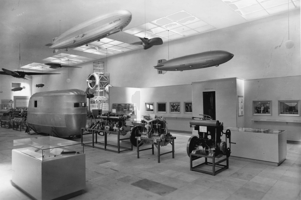 An der Decke befestigte Luftschiffmodelle, eine Gondel sowie technische Bauteile von Zeppelinen im damaligen Firmenmuseum.