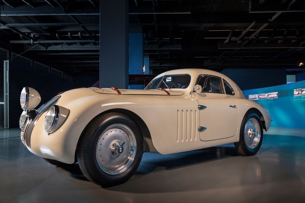 Die Ansicht zeigt ein cremefarbenes  kleines Automobil der Marke BMW. 