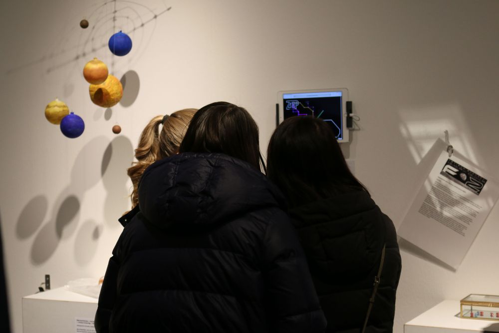 Drei Jugendlichen begutachten einen medialen Beitrag zur Ausstellung auf einem Tablet.