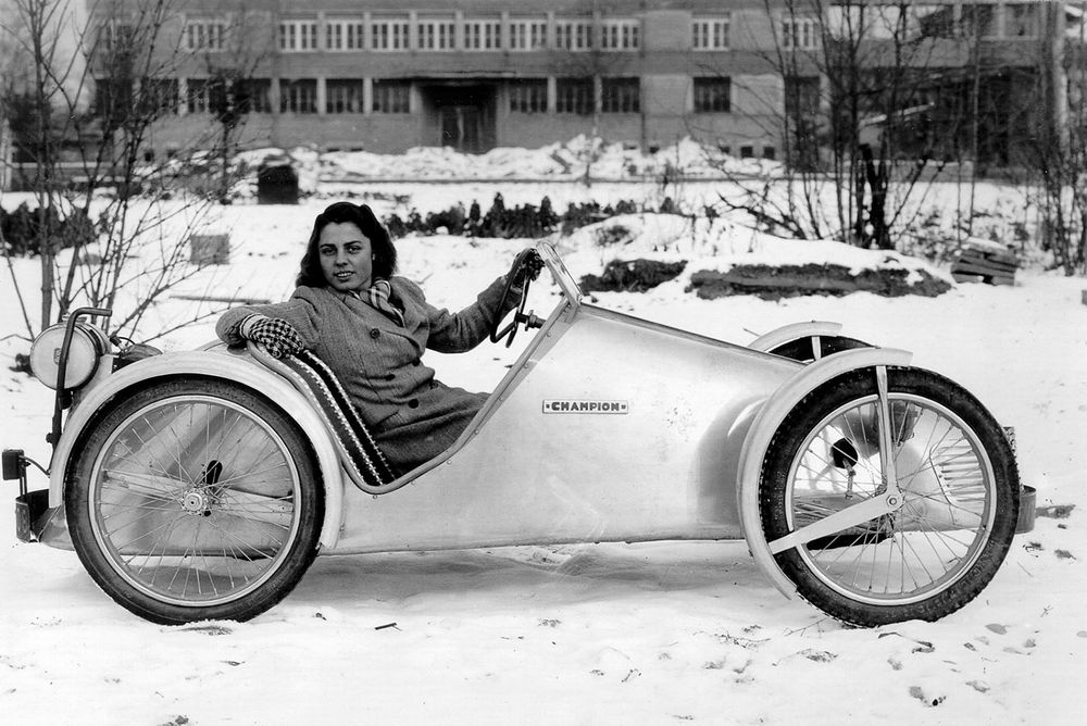 Historische Aufnahme einer Frau in einem alten Fahrzeug.