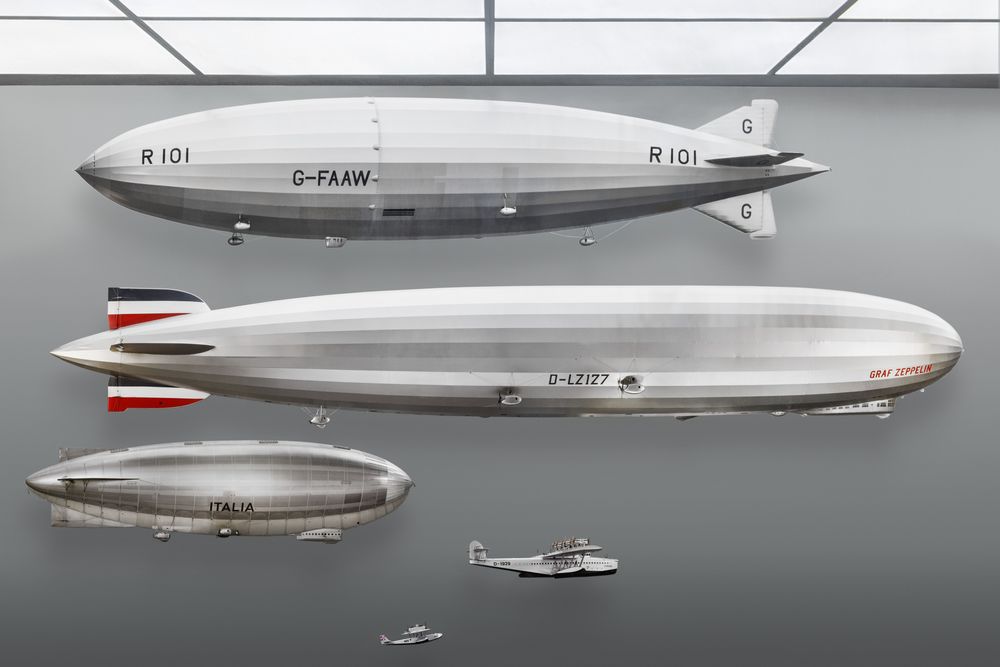 Mehrere Luftschiff Modelle in einer Vitrine. Das mittlere Modell ist LZ 127 Graf Zeppelin. Die Seitenleitwerke sind Schwarz-Weiß-Rot bemalt.