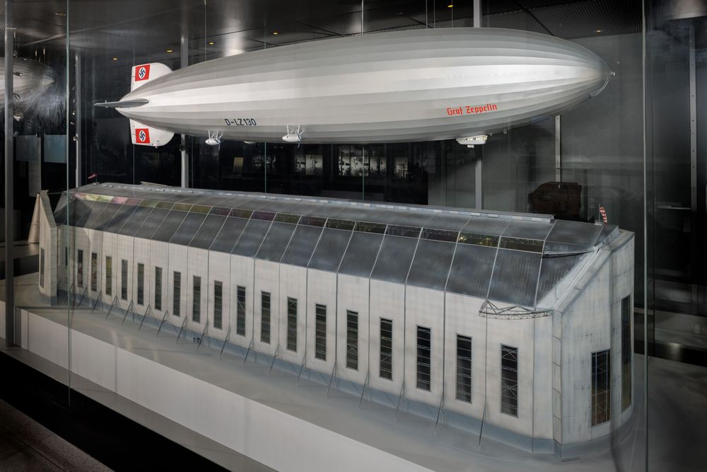 Foto des Modells LZ 130 der in einer Vitrine hängt. Unter ihm befindet sich ein Modell der Luftschiffhalle aus Frankfurt.