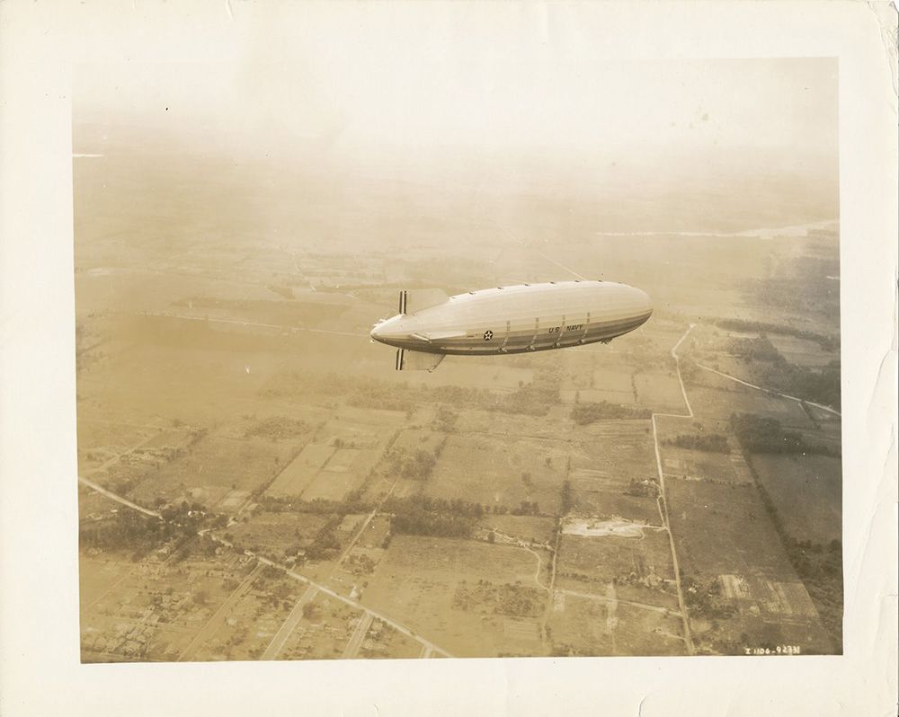 Die USS Akron bei ihrer Erstfahrt am 23. September 1931. Unter dem Luftschiff sind Felder und Grünflächen zu erkennen.