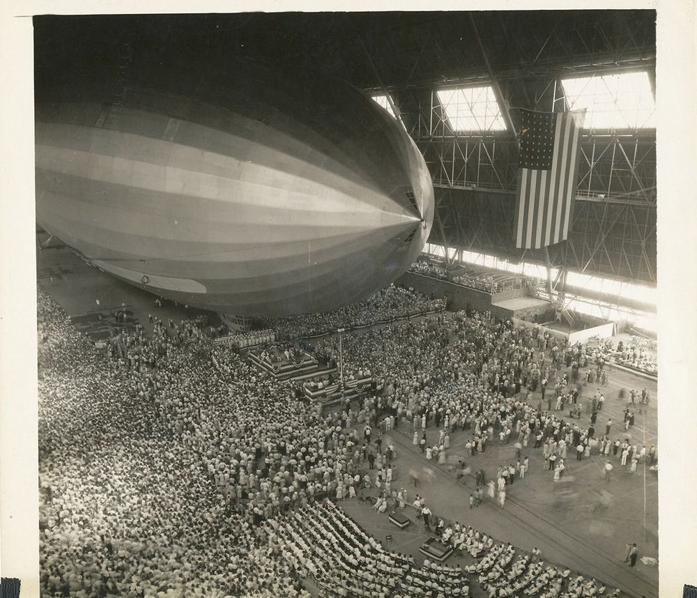 Vogelperspektive der feierlichen Taufe der USS Akron am 8. August 1931. Dutzende Personen befinden sich mit dem Luftschiff in der Halle.