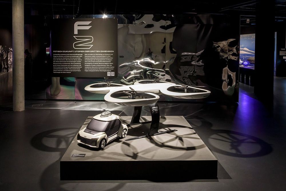 Die Ausstellungsansicht zeigt ein futuristisches Modell eines Autos und einem Flugobjekt der Marke Audi. 