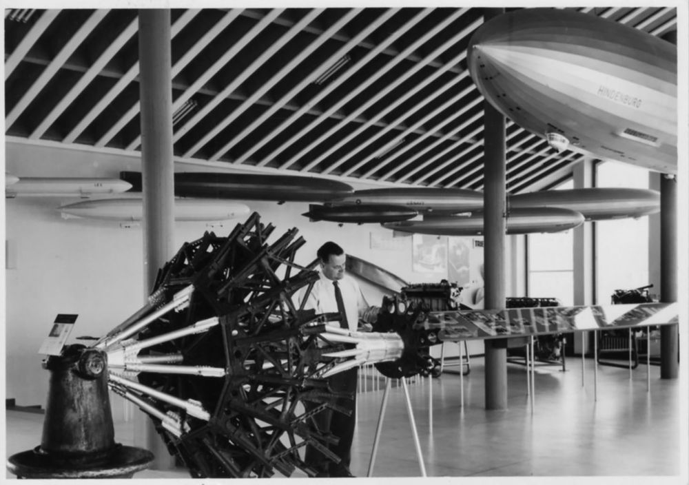 Blick in das Obergeschoss des Bodensee-Museums im Rathaus. Links im Vordergrund sieht man die Bugspitze des LZ 130 „Graf Zeppelin“ und einen Besucher rechts daneben. Unter der Decke hängen acht Zeppelinmodelle. 