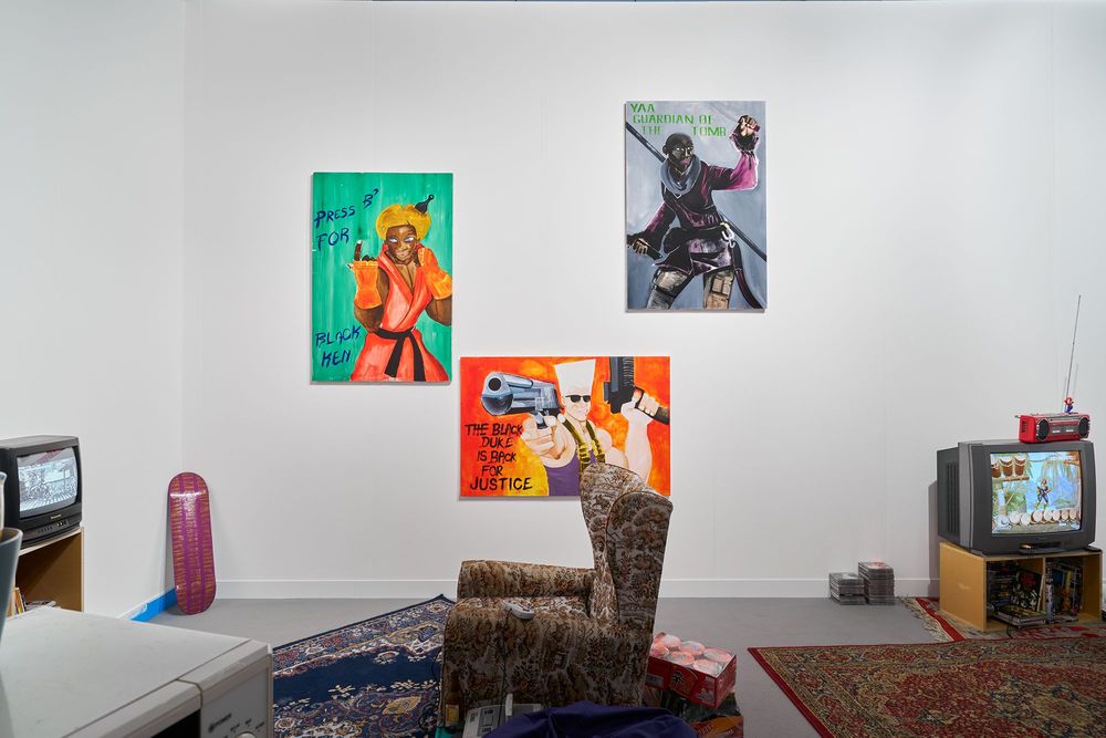 Installationsansicht auf Larry Achiampongs Jugendzimmer mit Teppichen, einem Sessel, mehreren Bildern an der Wand und zwei Bildschirmen.