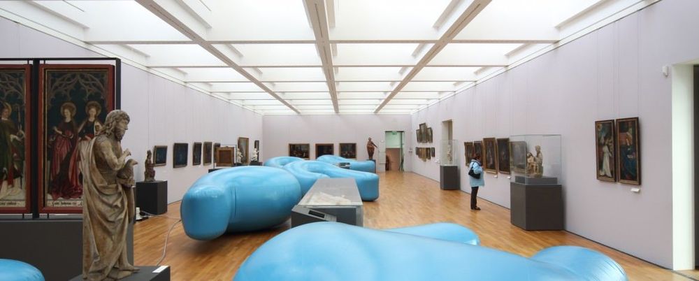 Die Ausstellungsansicht von "Luftkunst" zeigt große, blaue Objektkörper die im Raum zwischen Kunstexponaten liegen.