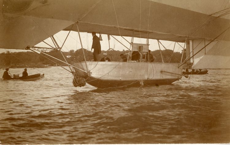 Das Luftschiff LZ 7 „Deutschland“ auf dem Bodensee. Mittig ist die Führergondel, darüber der Luftschiffkörper mit Stoffbespannung. In der Gondel sitzt Graf Zeppelin, der Luftschiffführer mit Besatzungsmitgliedern, die gerade den Start vorbereiten.