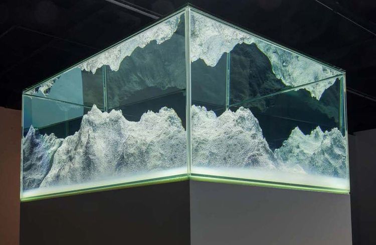 In einer Art Glaskasten oder Aquarium ist eine Berglandschaft aufgebaut.