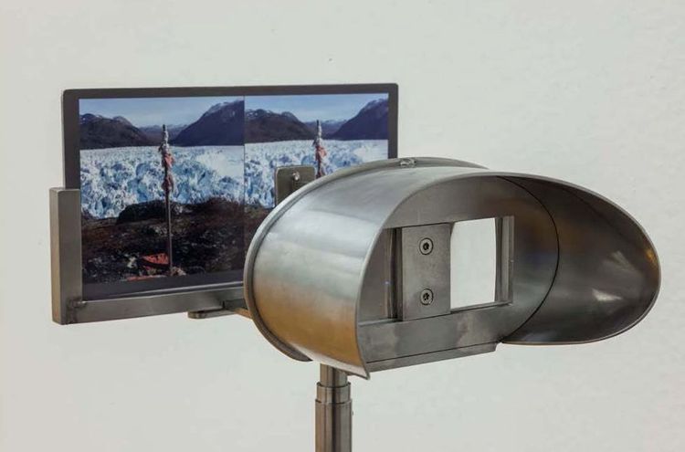 Die Aufnahme zeigt eine Art Fernrohr, vor dessen Linsen in einer Vorrichtung ein Bild eingespannt ist. Schaut man durch das Fernrohr blickt man automatisch auf das Bild.