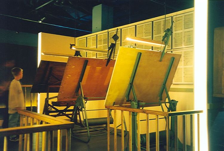 Die Ausstellungsansicht von "Zirkel, Zangen und Celon" zeigt einen Jungen der sich verschiedene Schriften an der Wand und auf der Ausstellungsfläche anschaut.
