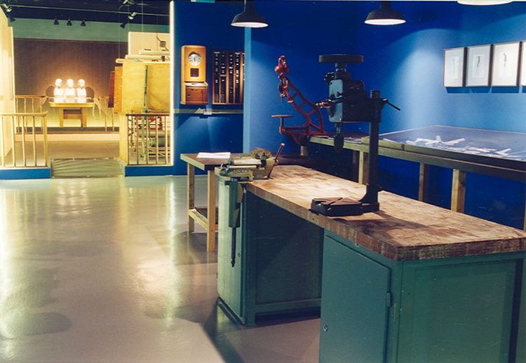 Die Ausstellungsansicht von "Zirkel, Zangen und Celon" zeigt eine große Ausstellungsfläche mit Tischen auf denen sich verschiedene Maschinen und Werkzeuge befinden.