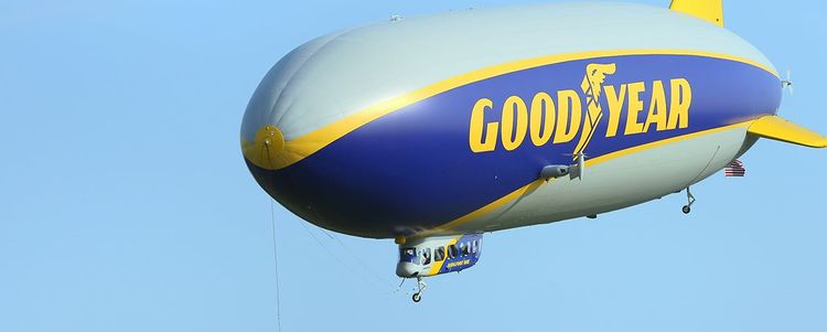 Ein Zeppelin NT mit dem gelben Schriftzug Goodyear schwebt vor blauem Himmel.