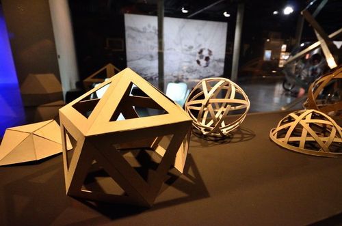 Auf einer Erhöhung befinden sich mehrere geometrische Objekte mit Aussparungen aus Pappe.