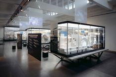 Eine lichtdurchflutete Ausstellungsfläche mit mehreren Informationstafeln und großen Glasvitrinen, in denen sich Objekte befinden. Die weiß gestrichene Decke mit vielen Fenstern bietet der Ausstellungsfläche viel Licht.