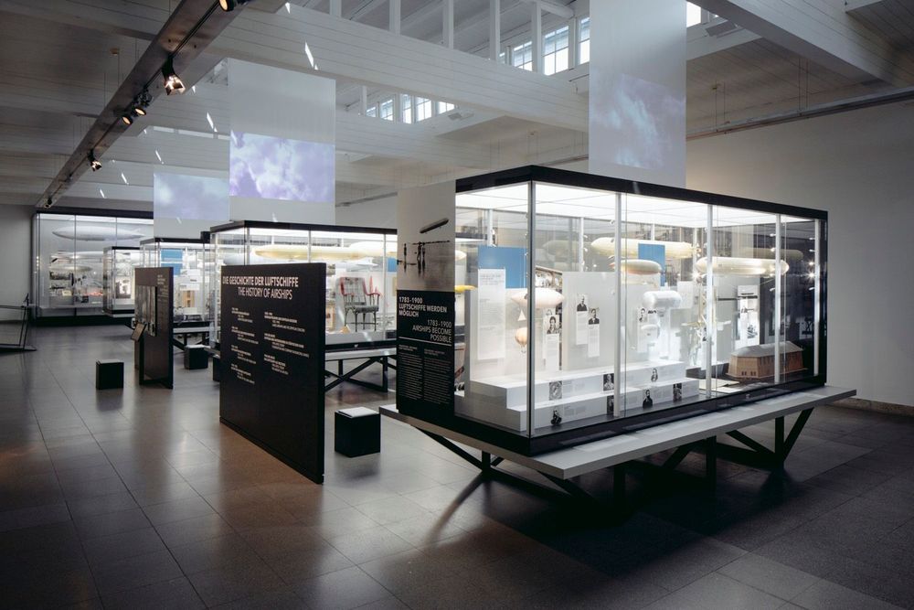 Ausstellungsansicht der Technikausstellung im Zeppelin Museum, verschiedene Personen schauen sich Vitrinen, Fotos und Texte zur Luftschifffahrtsgeschichte.